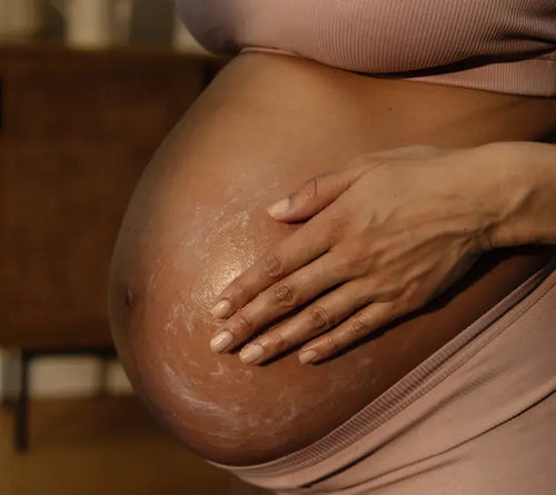Grávida gentilmente passando creme hidratante na sua barriga. - Mustela Brazil - 1