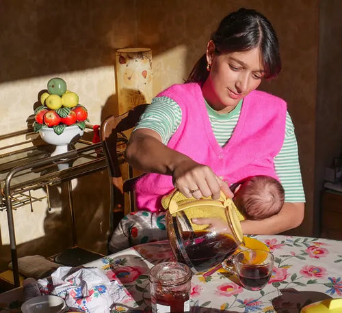 Mãe amamentando bebê e ao mesmo tempo servindo uma xícara de chá para ela mesma. - Mustela Brazil - 1