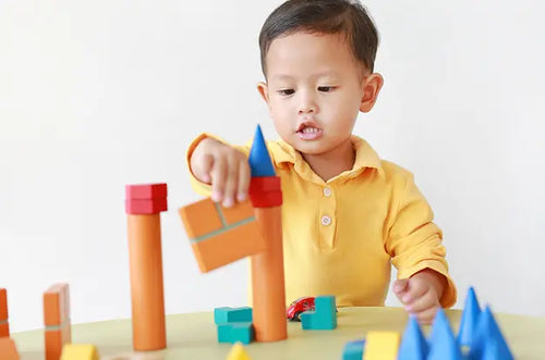 Menino brinca com blocos de madeira sobre mesa em escola. - Mustela Brazil - 1