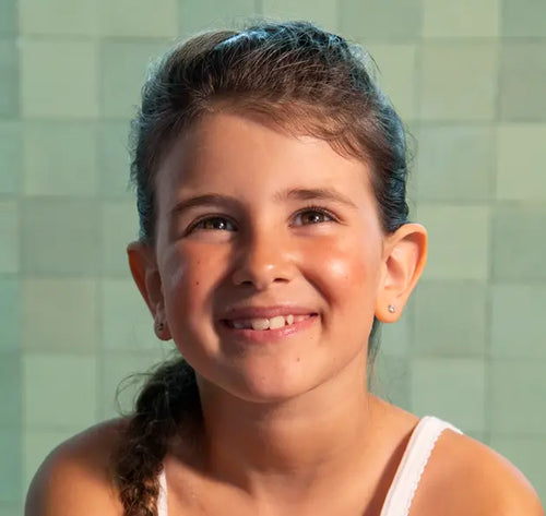Menina sorridente olhando para a câmera. Suas bochechas tem manchas avermelhadas. - Mustela Brasil - 1