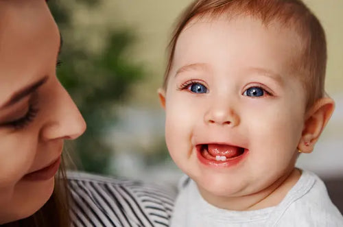 Bebê sorridente mostrando seus primeiros 2 dentinhos. - Mustela Brasil - 1