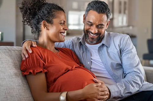 Homem abraça mulher grávida e apoia sua mão em sua barriga. - Mustela Brasil - 1