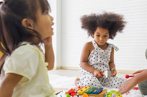 Meninas brincam juntas sentadas no chão. - Mustela Brasil - 1