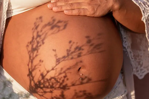 Barriga de mulher grávida com sombra de árvore projetada nela. - Mustela Brasil - 1