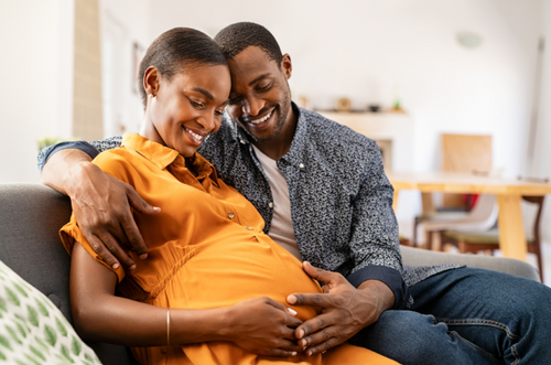 Homem abraçando carinhosamente uma mulher grávida, ambos estão com as mãos sobre a barriga da grávida. - Mustela Brasil - 1