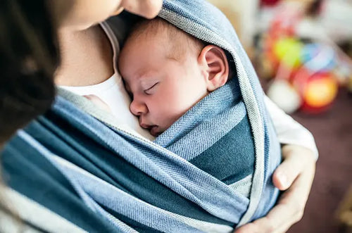 Mãe segura bebê com sling, o bebê dorme tranquilamente. - Mustela Brasil - 1