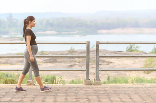 Mulher grávida com roupas confortáveis caminhando à beira de um rio. - Mustela Brasil - 1