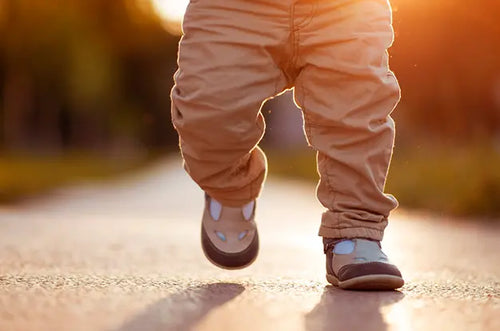 Bebê de sapato andando em rua ao por do sol. - Mustela Brasil - 1