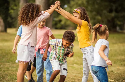 Crianças brincando em parque de passar por debaixo dos braços estendidos de duas crianças. - Mustela Brasil - 1
