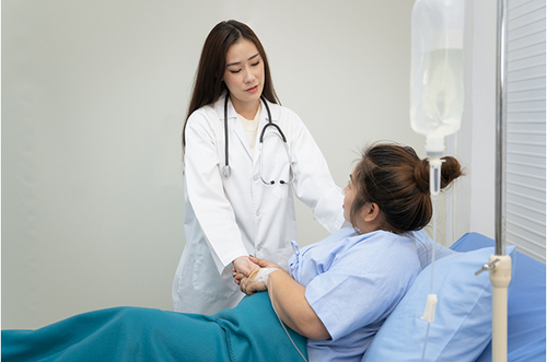 Grávida em maca de hospital segurando as mãos de uma médica com expressão tranquila. - Mustela Brasil - 1