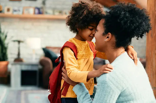 Mãe abraça filha que está de mochila pronta para ir à escola. - Mustela Brasil - 1